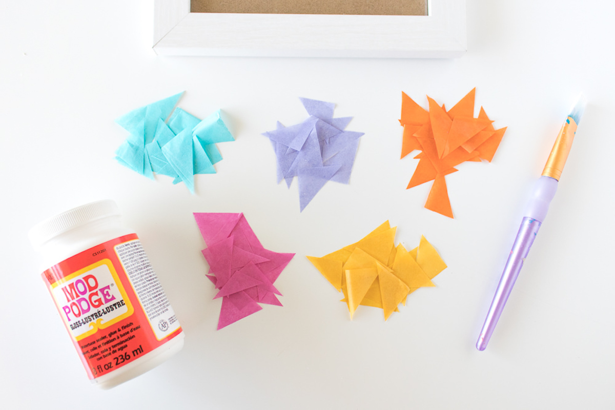 bottle of Mod Podge with tissue paper triangles and a paintbrush