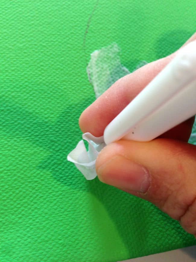 Placing tissue paper into the wet Mod Podge on the canvas