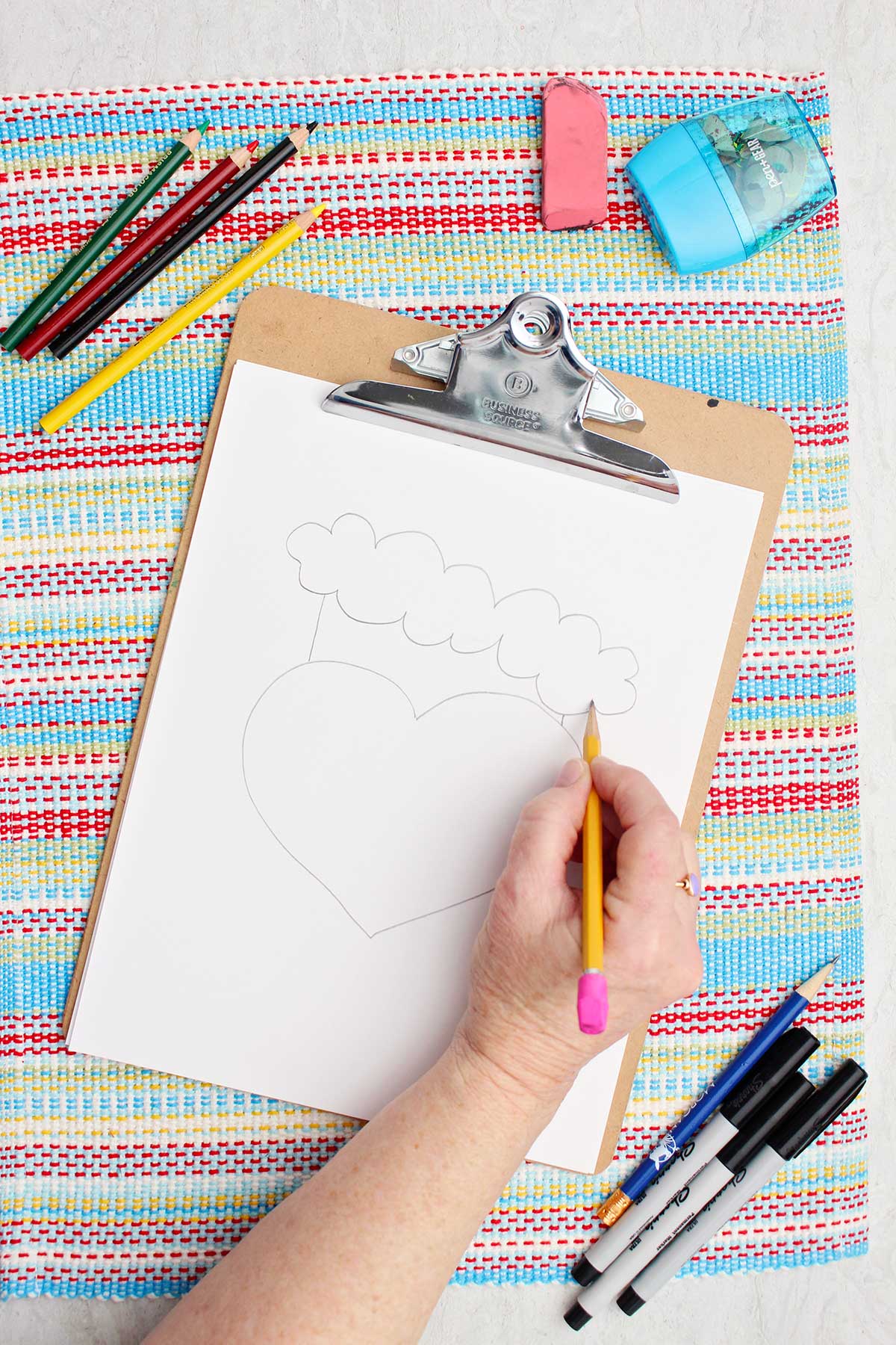 Person adding some trim details on the Santa hat of their Grinch sketch.