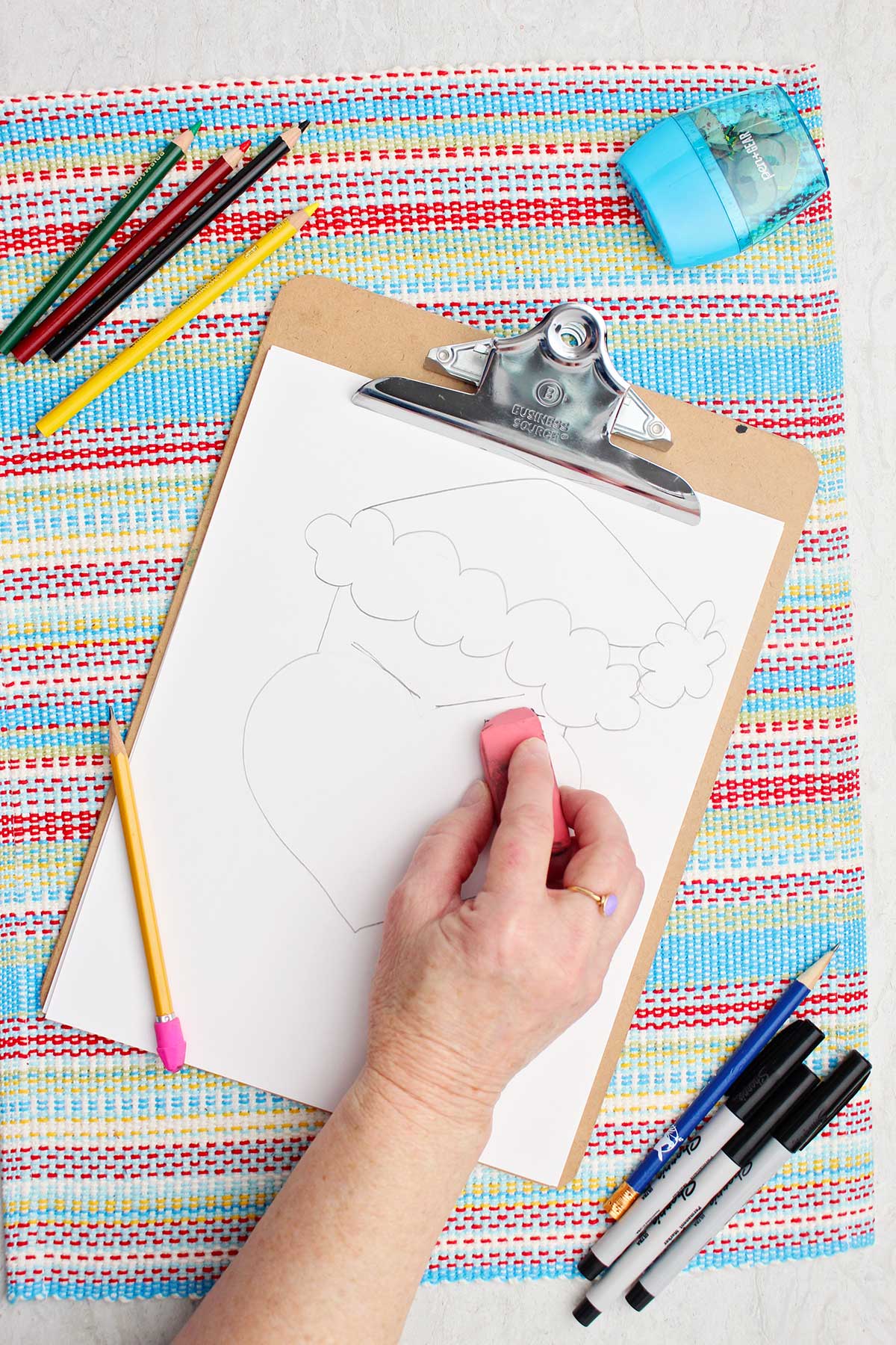 Person erasing some lines near the eyes on their Grinch sketch.