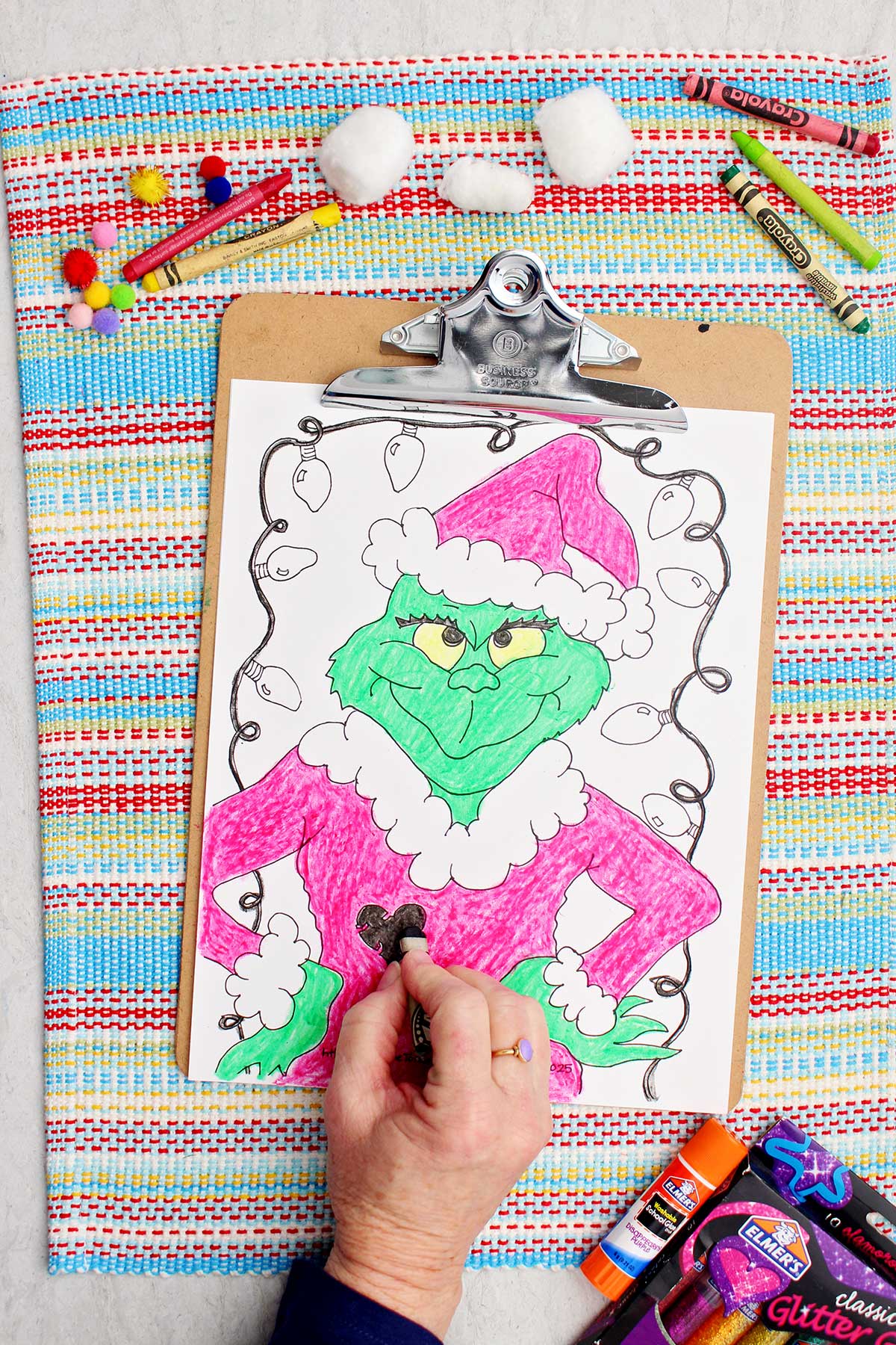 Person coloring heart on coat on Grinch coloring page.