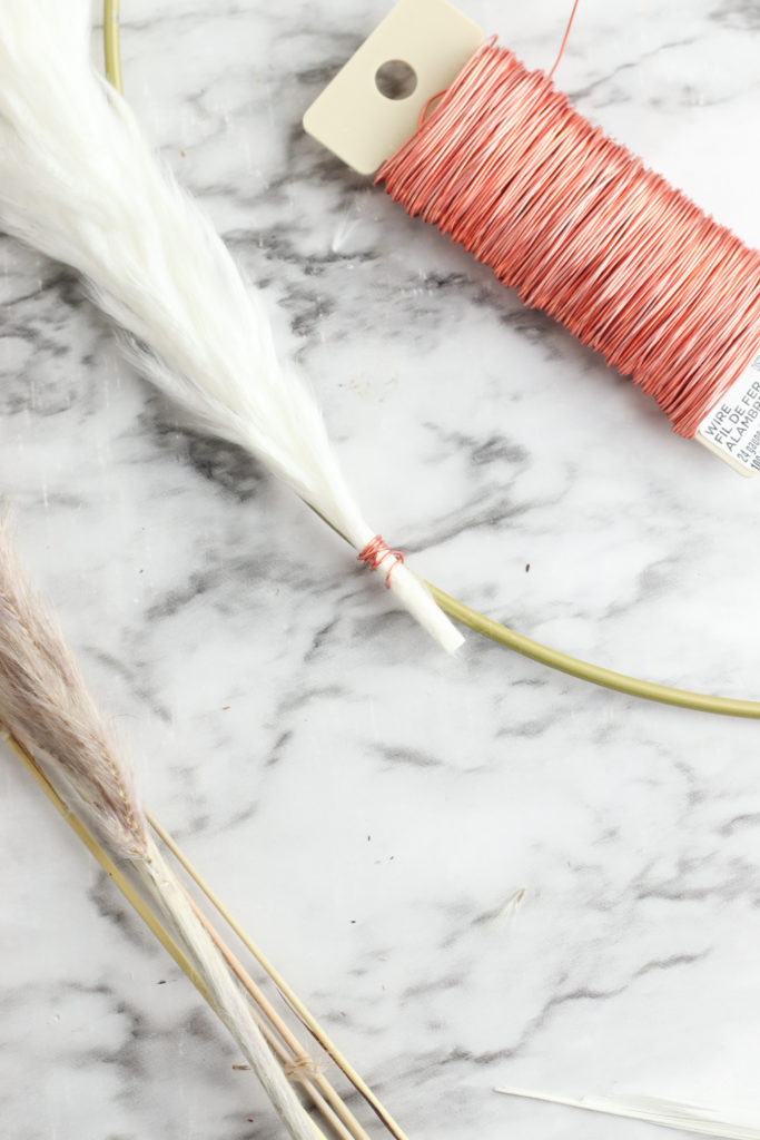 Securing pampas grass to the hoop wreath with floral wire.