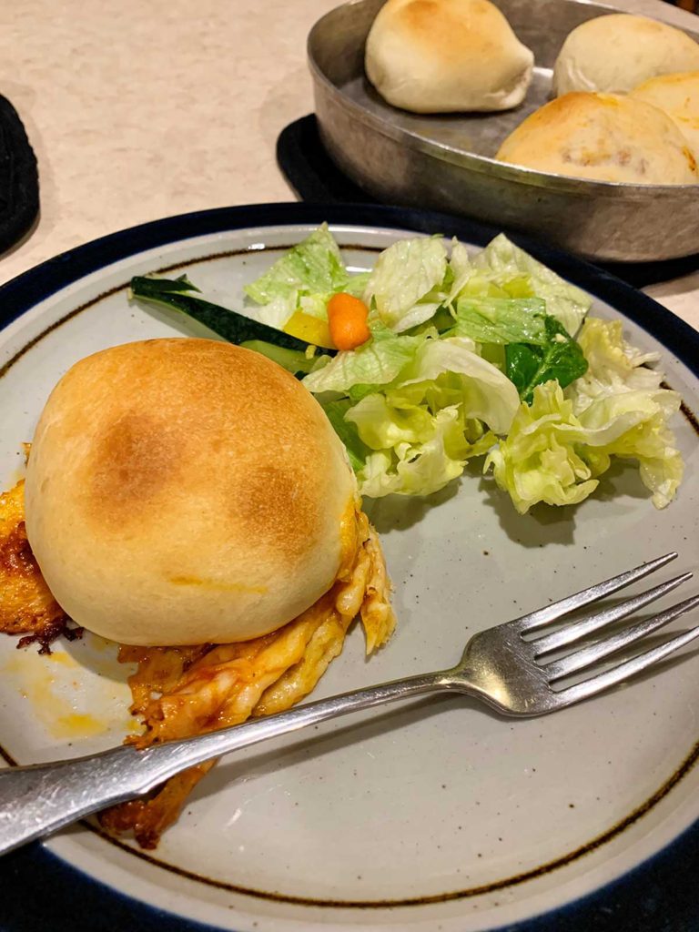 Homemade pizza pockets with cheese on a dinner plate with a salad.