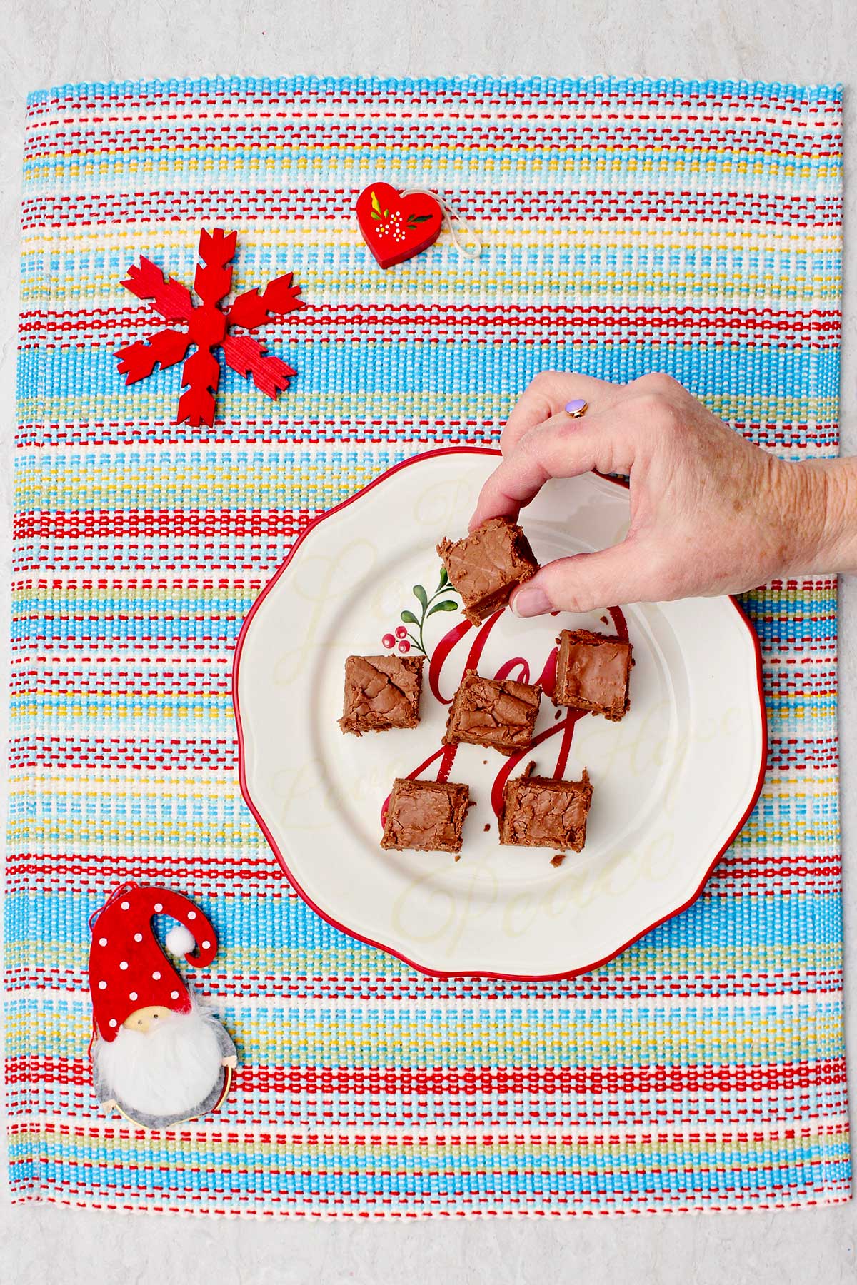 A person picking up a piece of fudge off of a holiday plate.