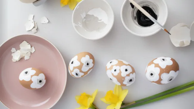 Design Easter eggs in the Marimekko style, brown eggs with white flowers are painted