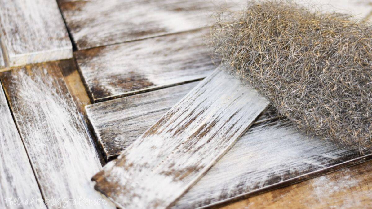 Make new wood look OLD with this tutorial on how to Weather Wood. Click through for instructions Distressed wood planks with a weathered finish, shown alongside steel wool used to create a rustic, aged wood texture.