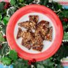 A red rimmed plate of toffee surrounded by festive ivy.
